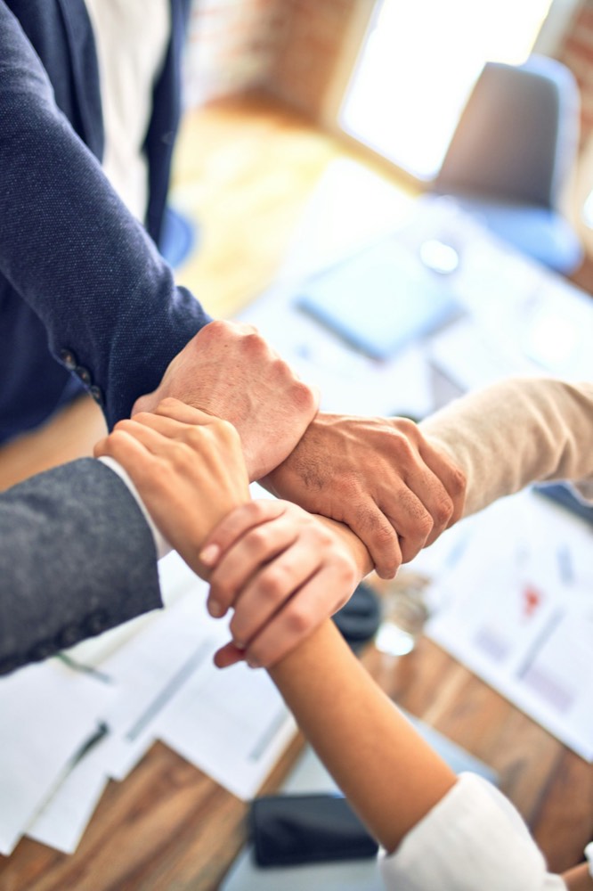 Mains unies autour d'une table, engagement collectif